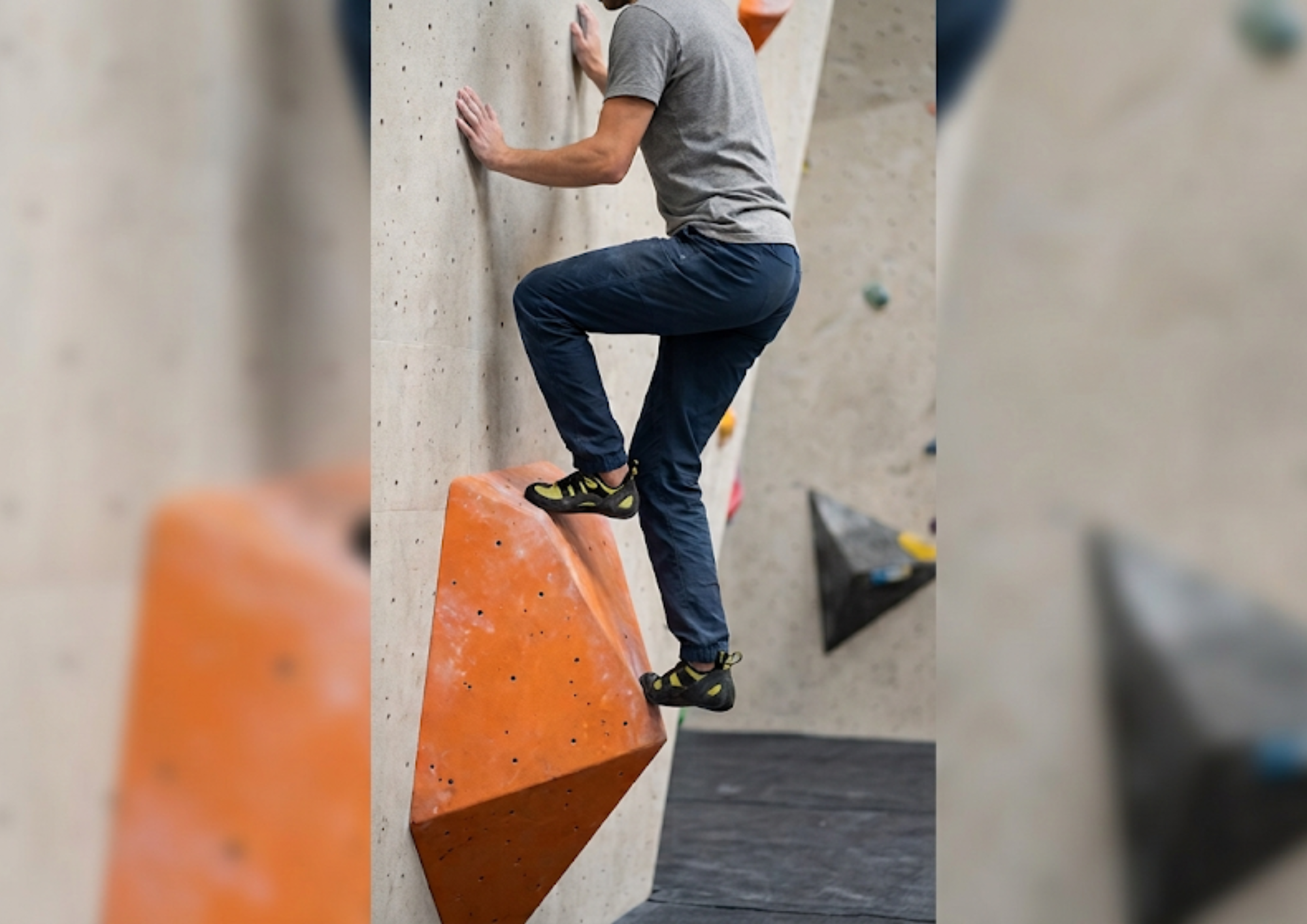 Grimpeur en placement de pied sur un volume orange en salle de bloc